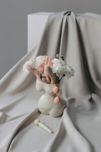 Elegant still life with minimalistic vase and soft pastel flowers on draped fabric.