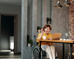 Woman in a wheelchair enjoying remote work and video call at home in a modern interior.