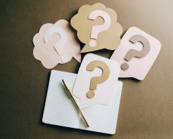 Flat lay of question mark paper crafts on a notebook, symbolizing questions and ideas.